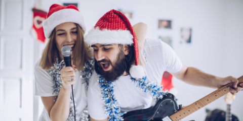 a couple in festive hats singing christmas music